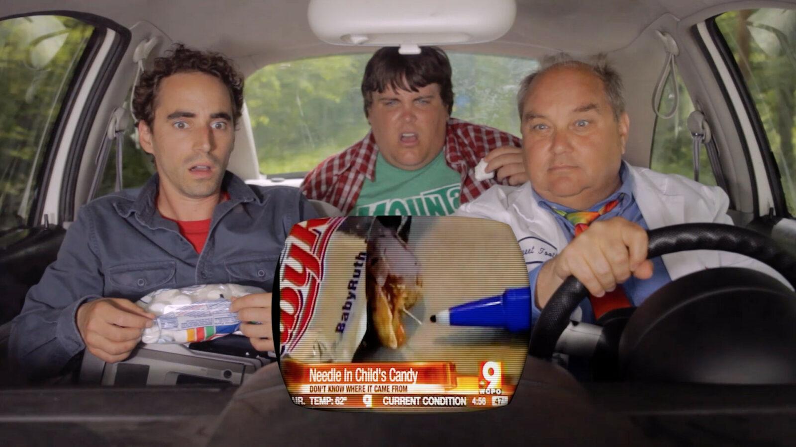 3 guys in a car watching a tv in the car