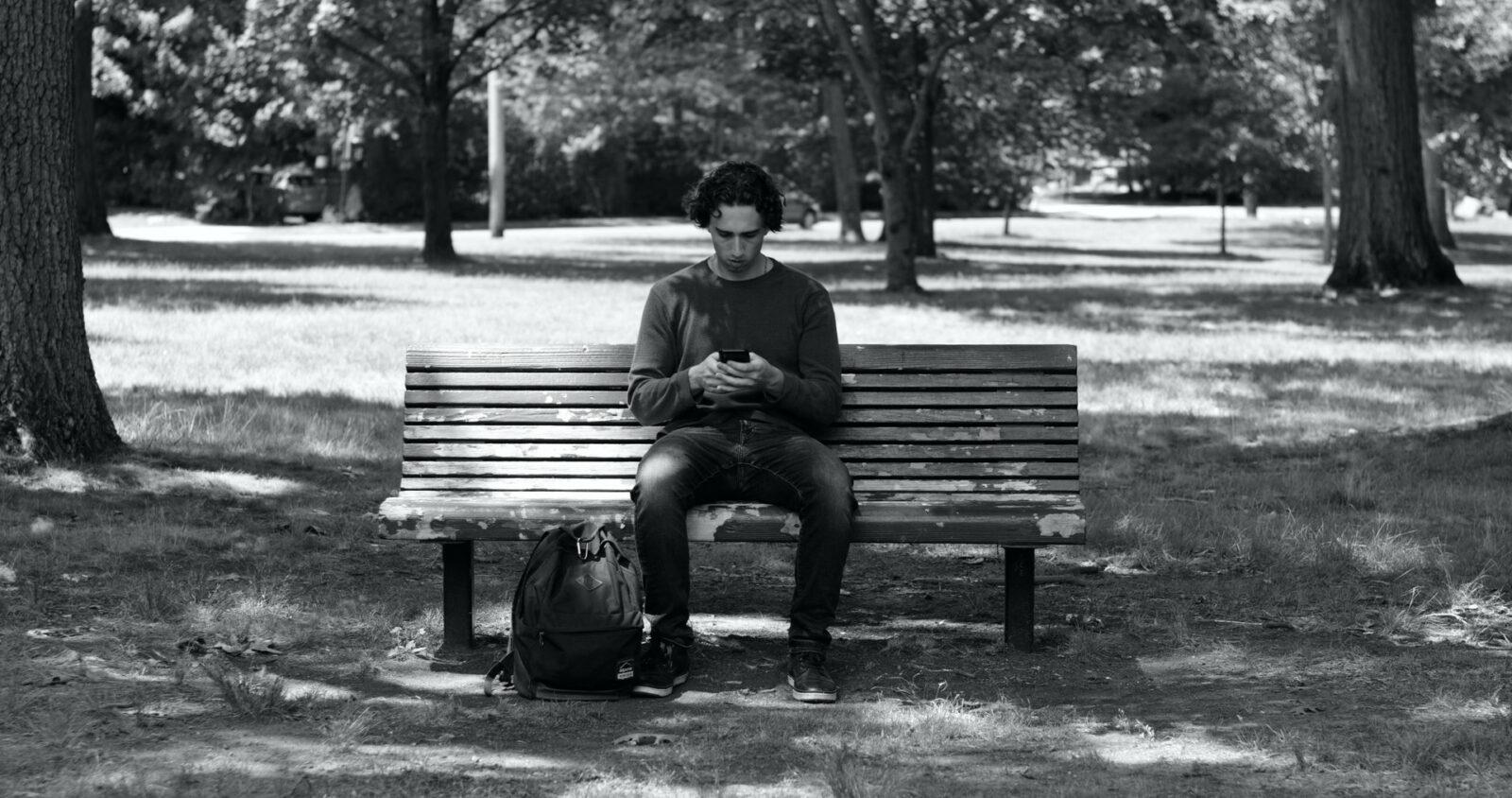 A man sitting on the bench looking at his phone.